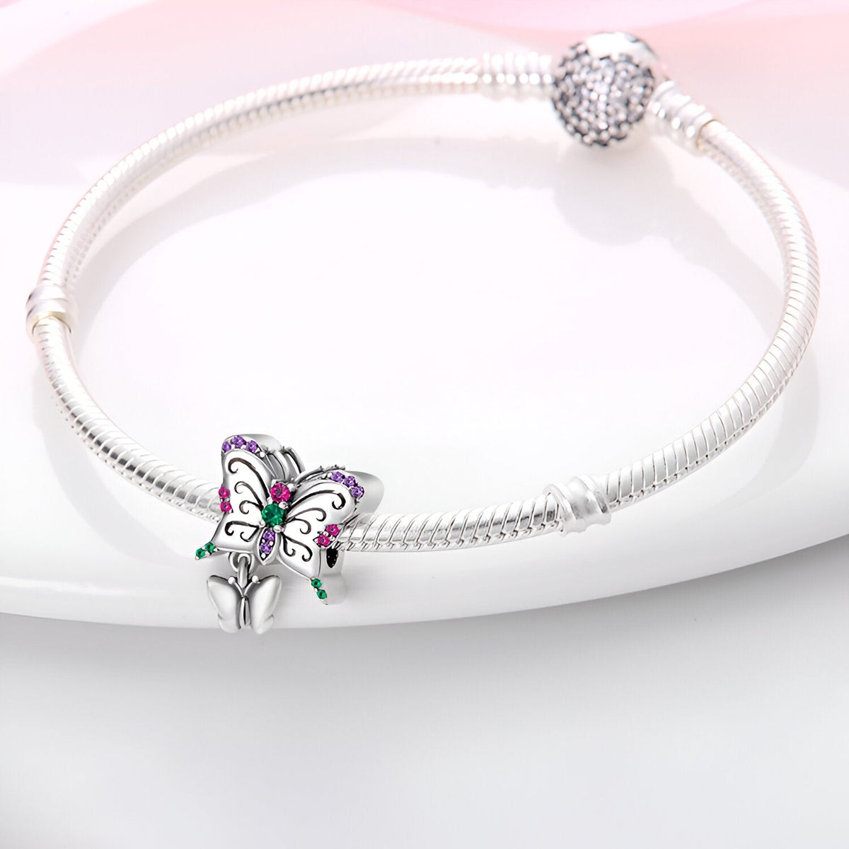 Bracelet argenté rigide avec charm duo papillons ornés de strass multicolores.