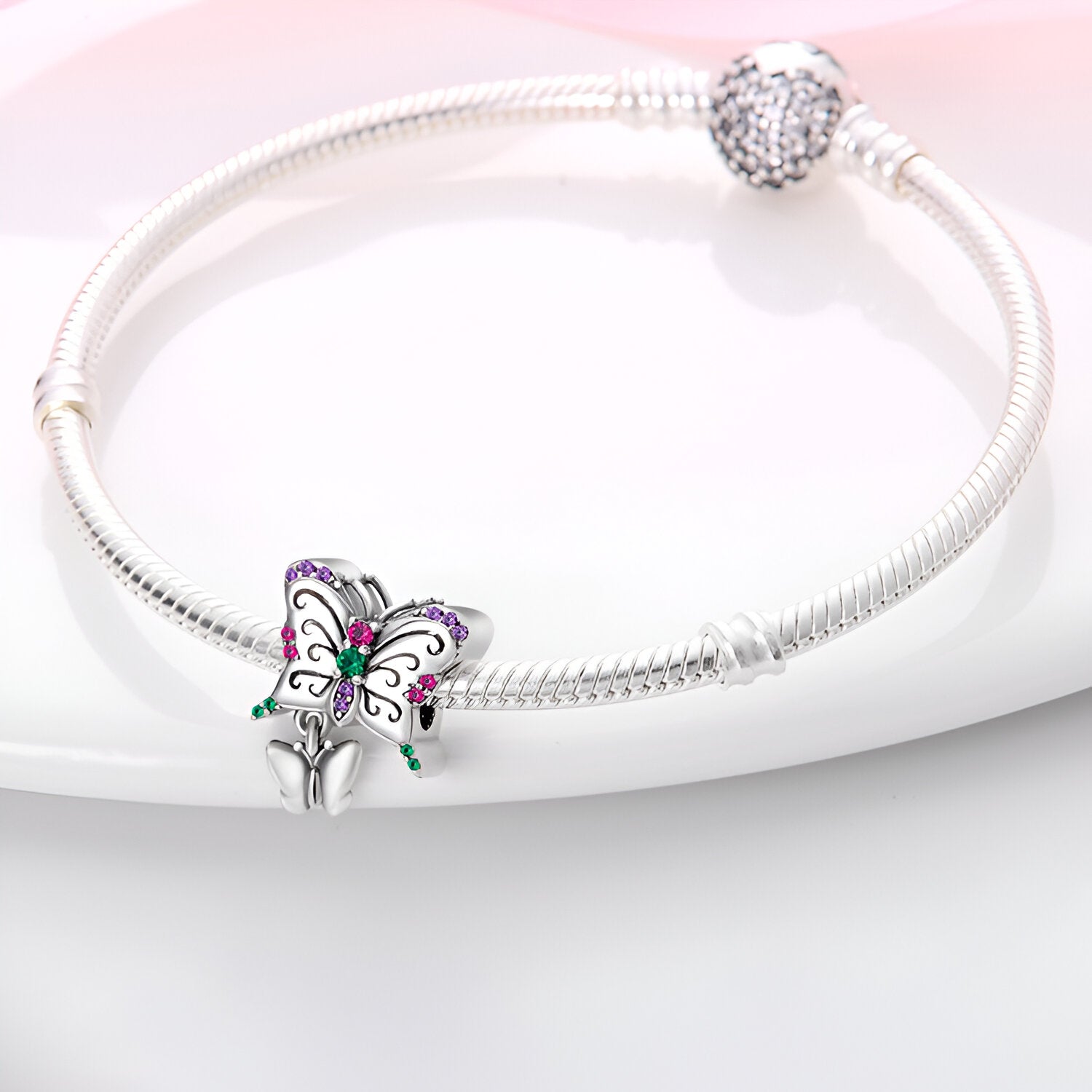 Bracelet argenté rigide avec charm duo papillons ornés de strass multicolores.