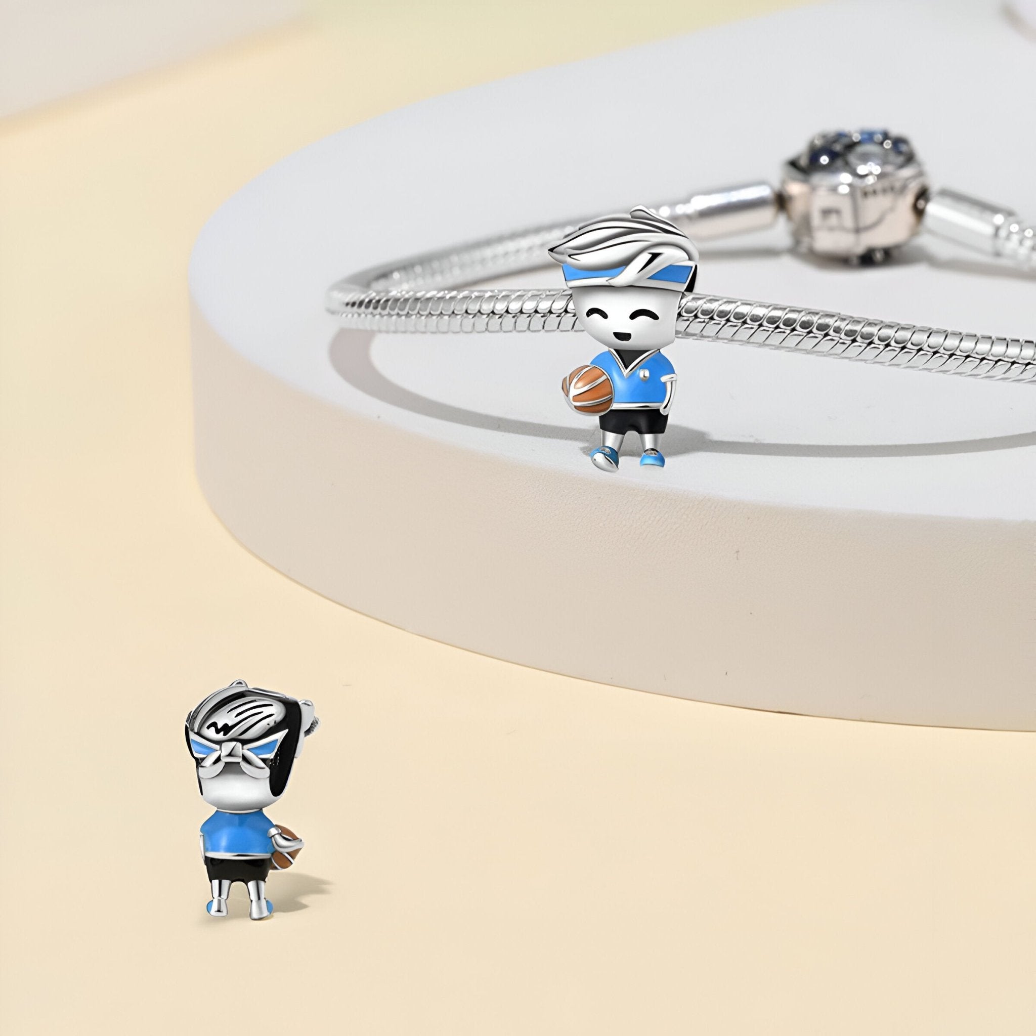 Charm en argent représentant un joueur de basket féminin avec maillot bleu et ballon orange.