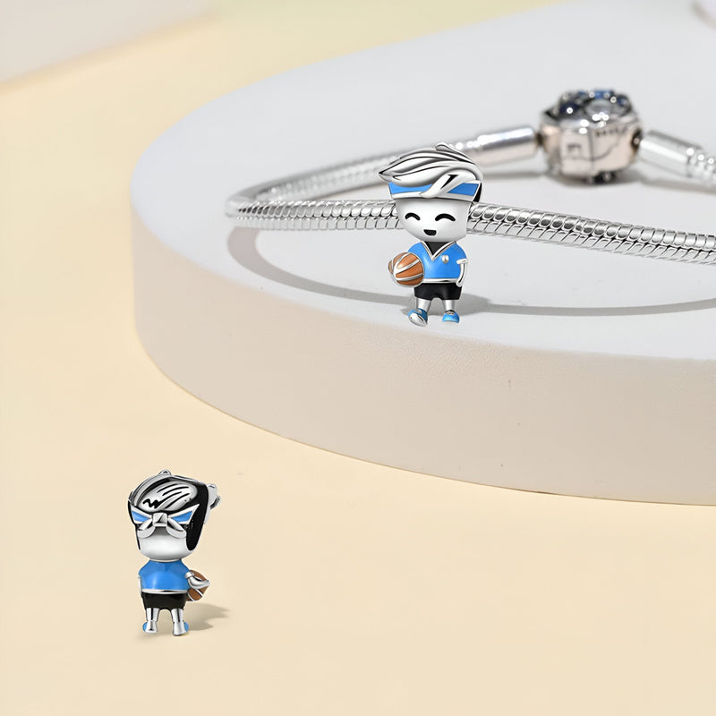 Charm en argent représentant un joueur de basket féminin avec maillot bleu et ballon orange.