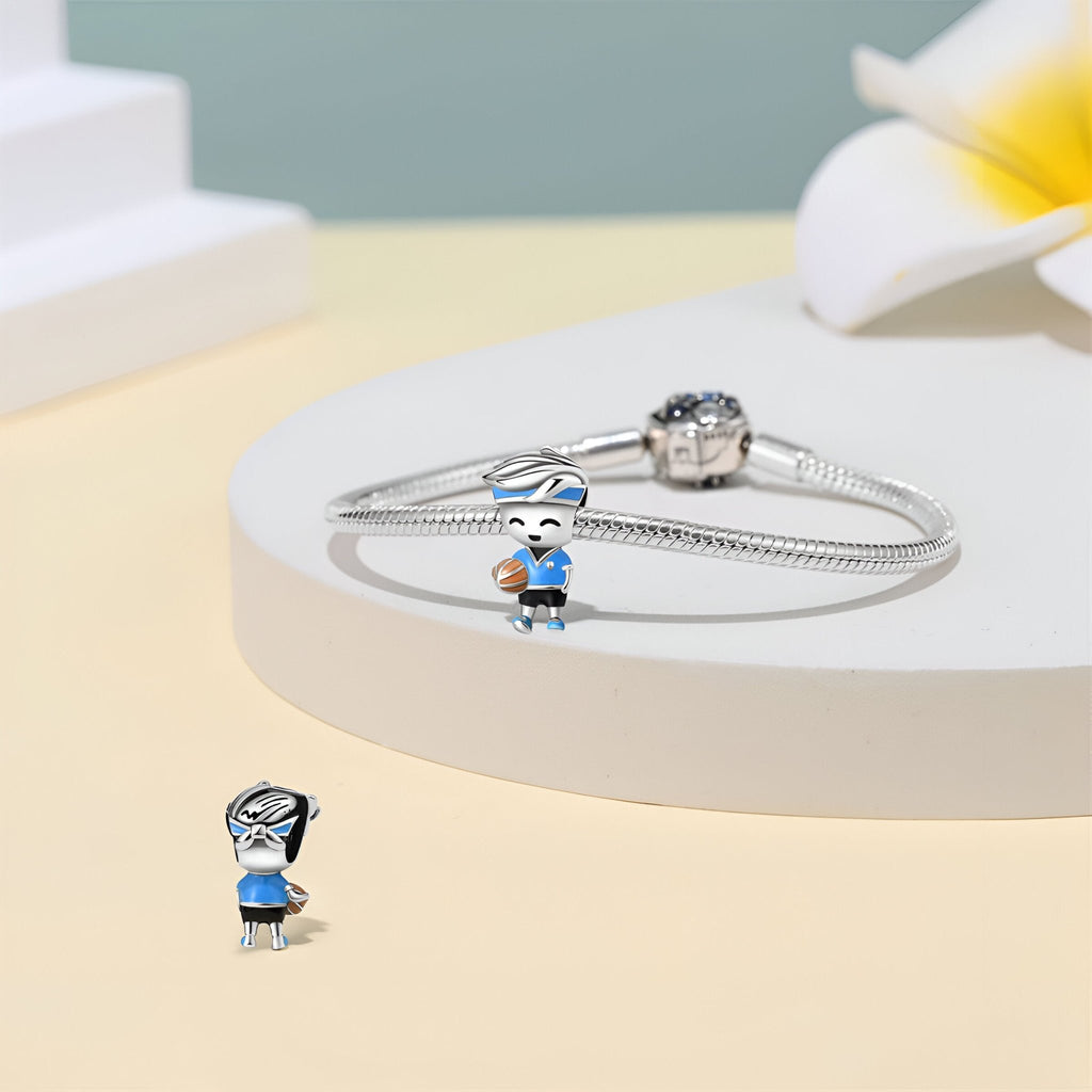 Charm en argent représentant un joueur de basket en tenue bleue et blanche sur un bracelet serpent en argent.