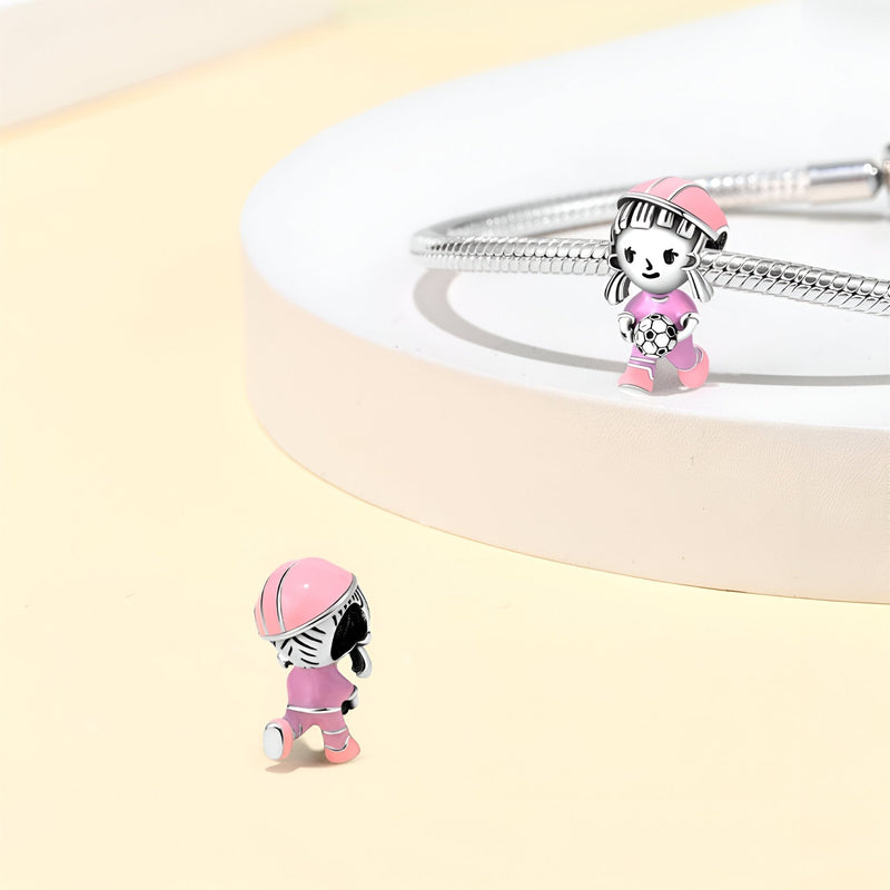 Charm en argent représentant une joueuse de football stylisée avec casque rose et tenue rose pâle.