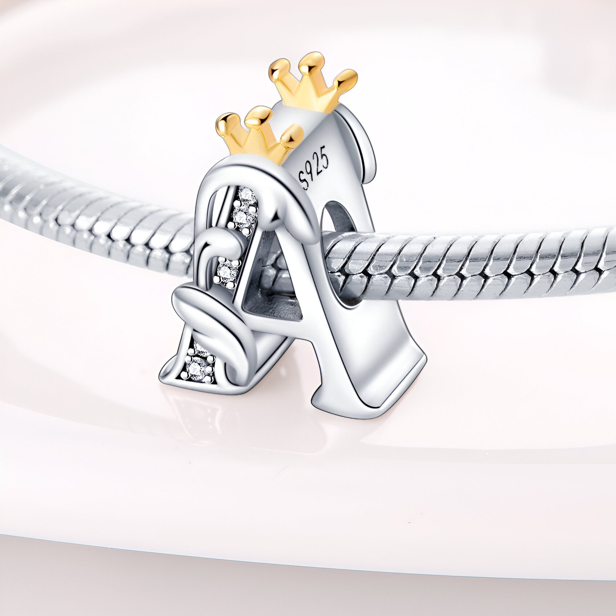 Charm lettre A en argent 925 avec petite couronne dorée, détail brillant, sur bracelet serpent argenté.