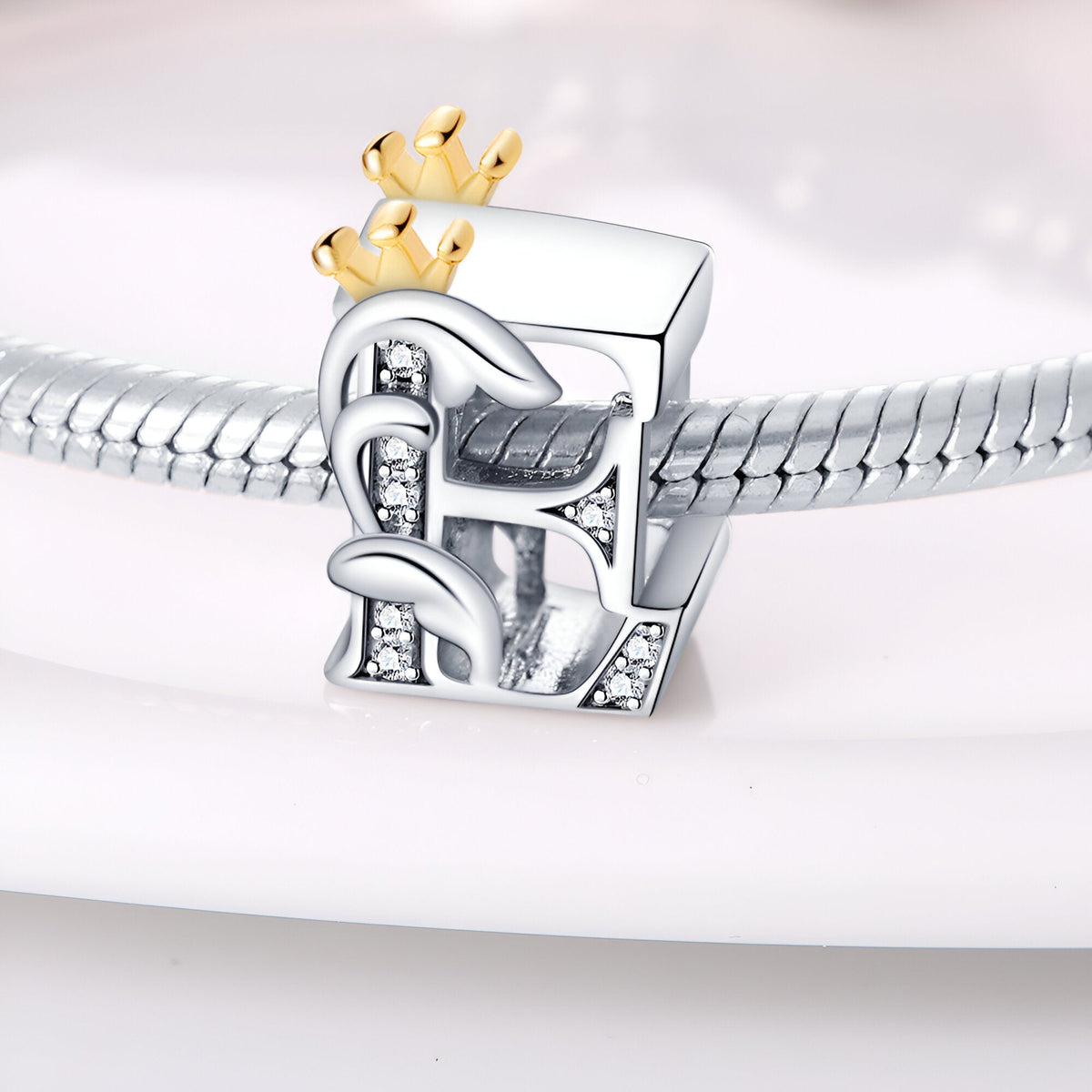 Charm lettre E en argent avec motifs floraux et couronne en or pour bracelet.