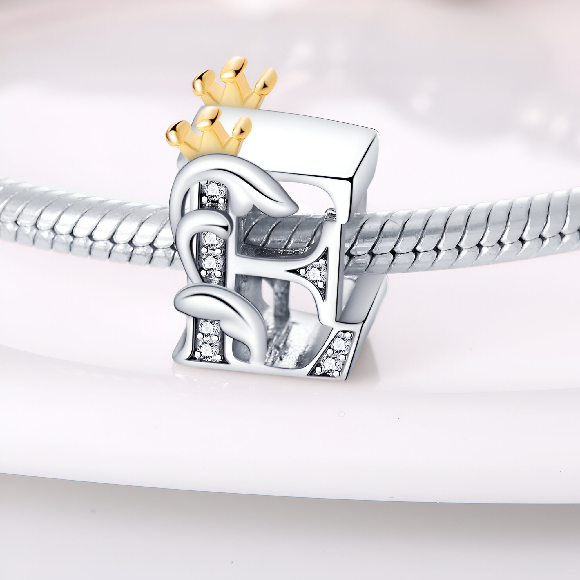 Charm lettre E en argent avec motifs floraux et couronne en or pour bracelet.