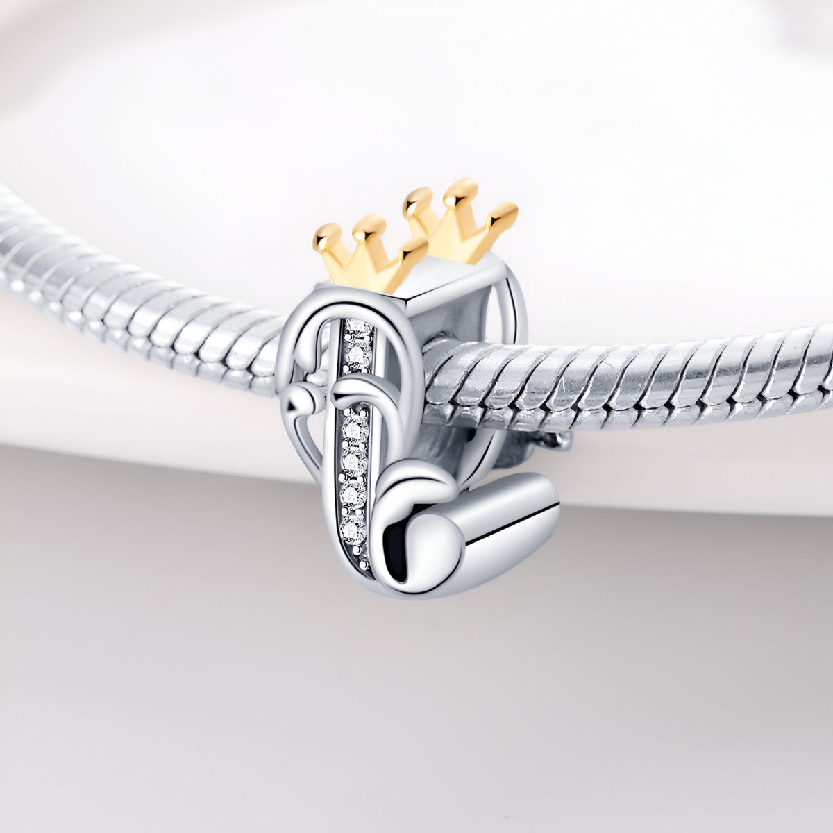 Charm lettre J en argent avec couronne dorée et petits strass, style élégant et raffiné.