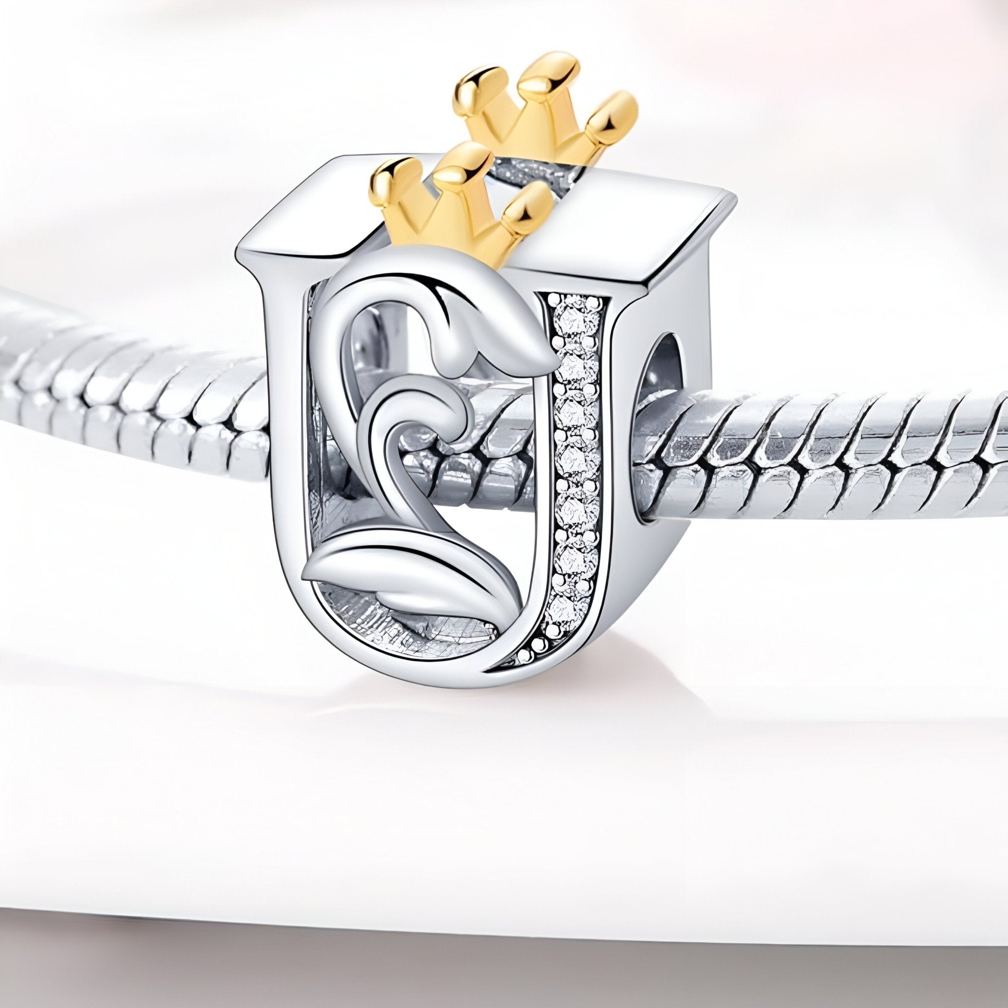 Charm lettre U en argent avec couronne dorée et détails en strass sur bracelet serpent acier.