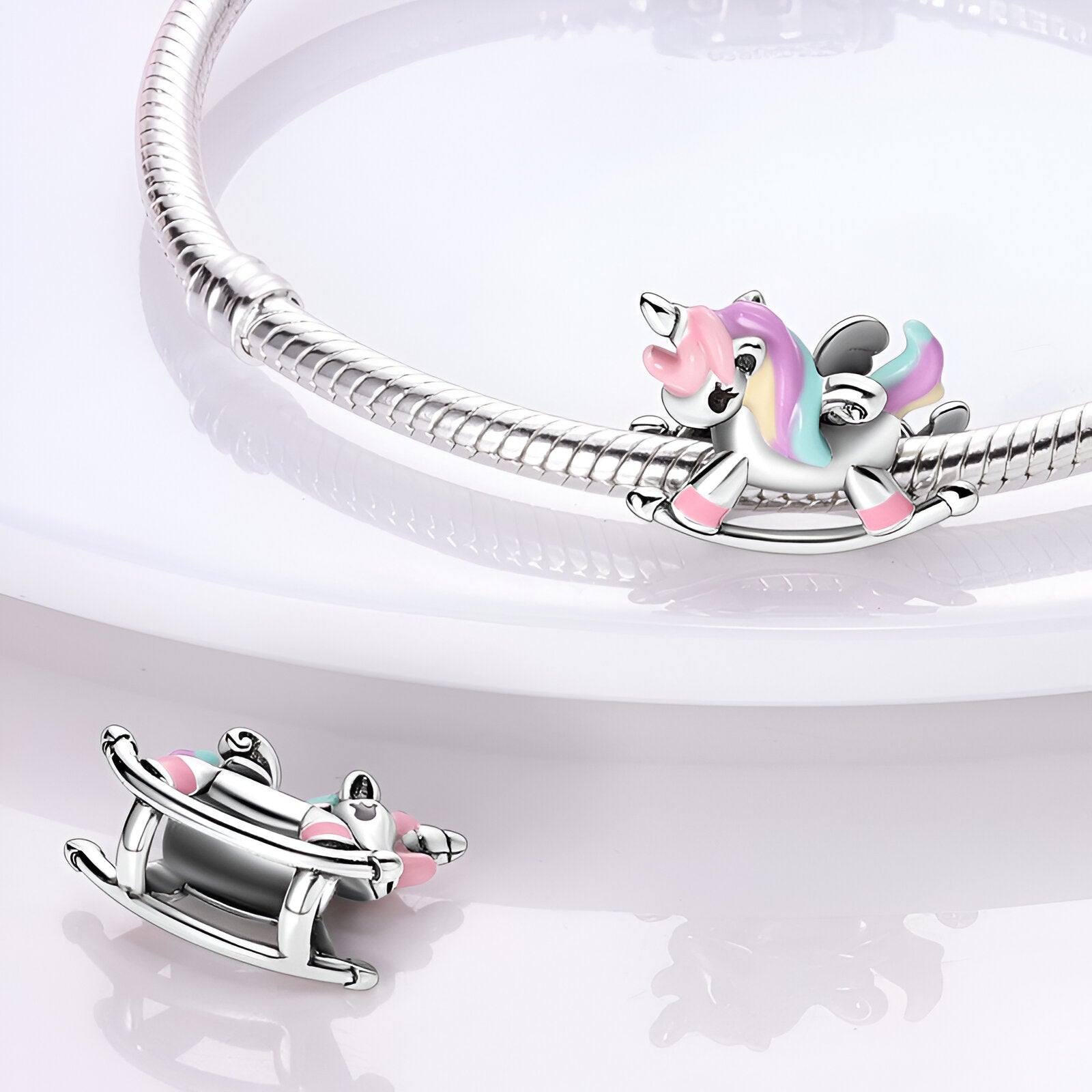 Charm en forme de licorne colorée rose et bleu avec ailes sur bracelet argenté.