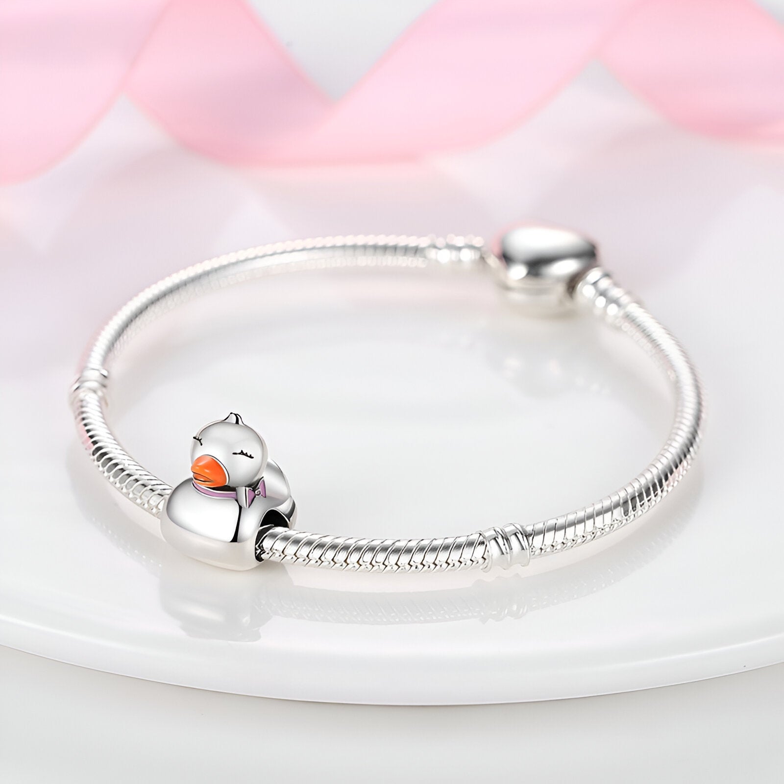 Bracelet argenté serpent avec charm canard en émail orange et blanc.