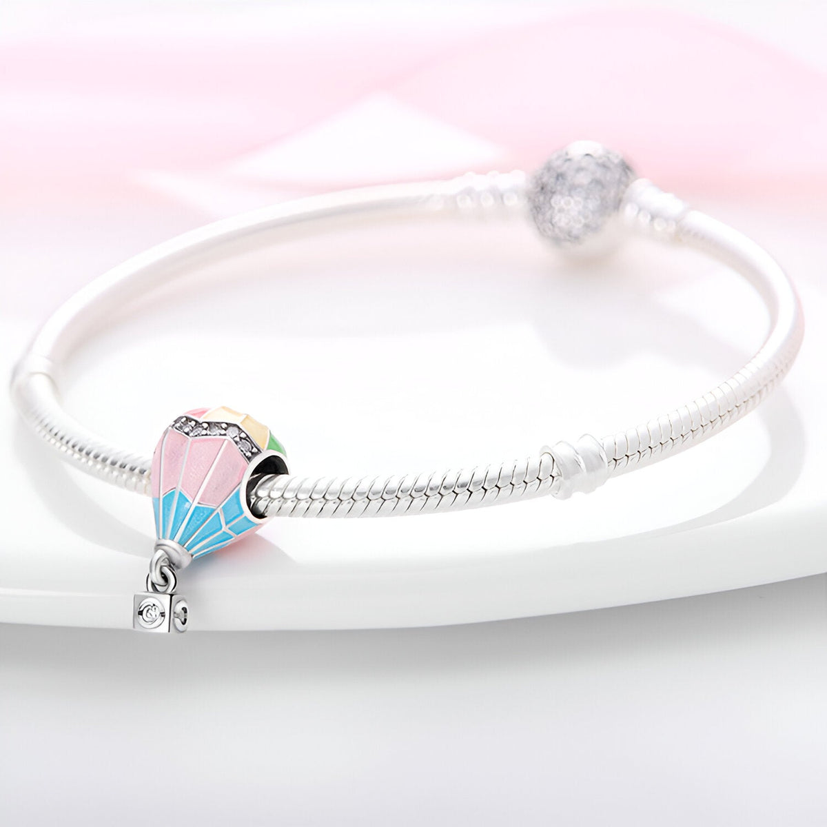 Charm montgolfière en argent avec émail rose et bleu sur bracelet serpent argenté.