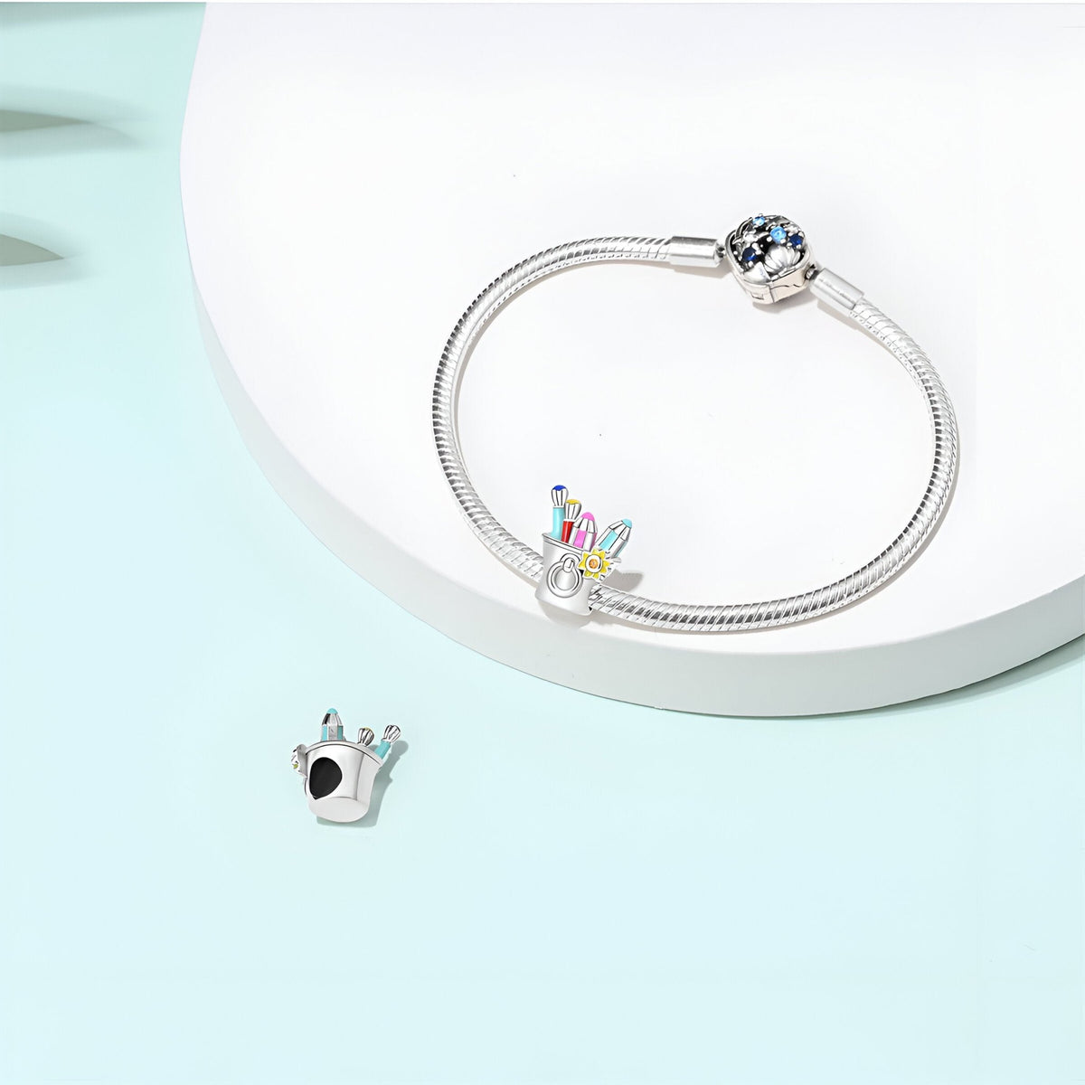 Bracelet argenté avec charm forme couronne et perle bleue étincelante, design délicat.