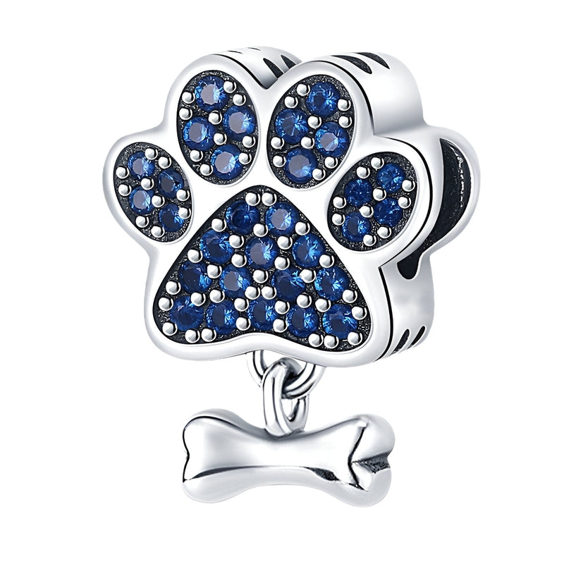 Charm argent en forme de patte de chien ornée de petits cristaux bleus avec os suspendu.