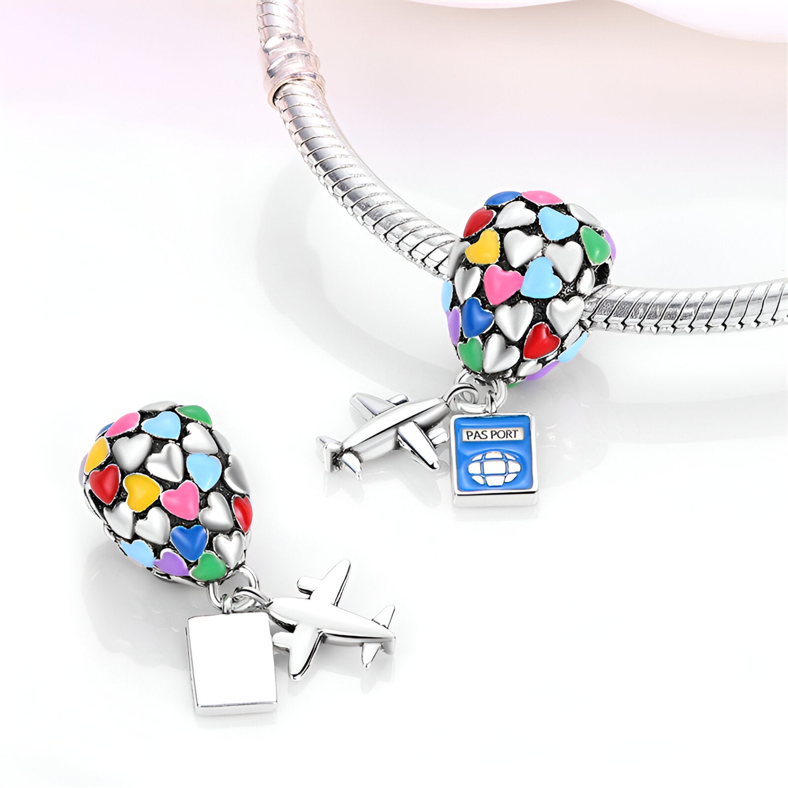 Charm pendentif en forme de montgolfière multicolore et avion argenté sur bracelet serpent.