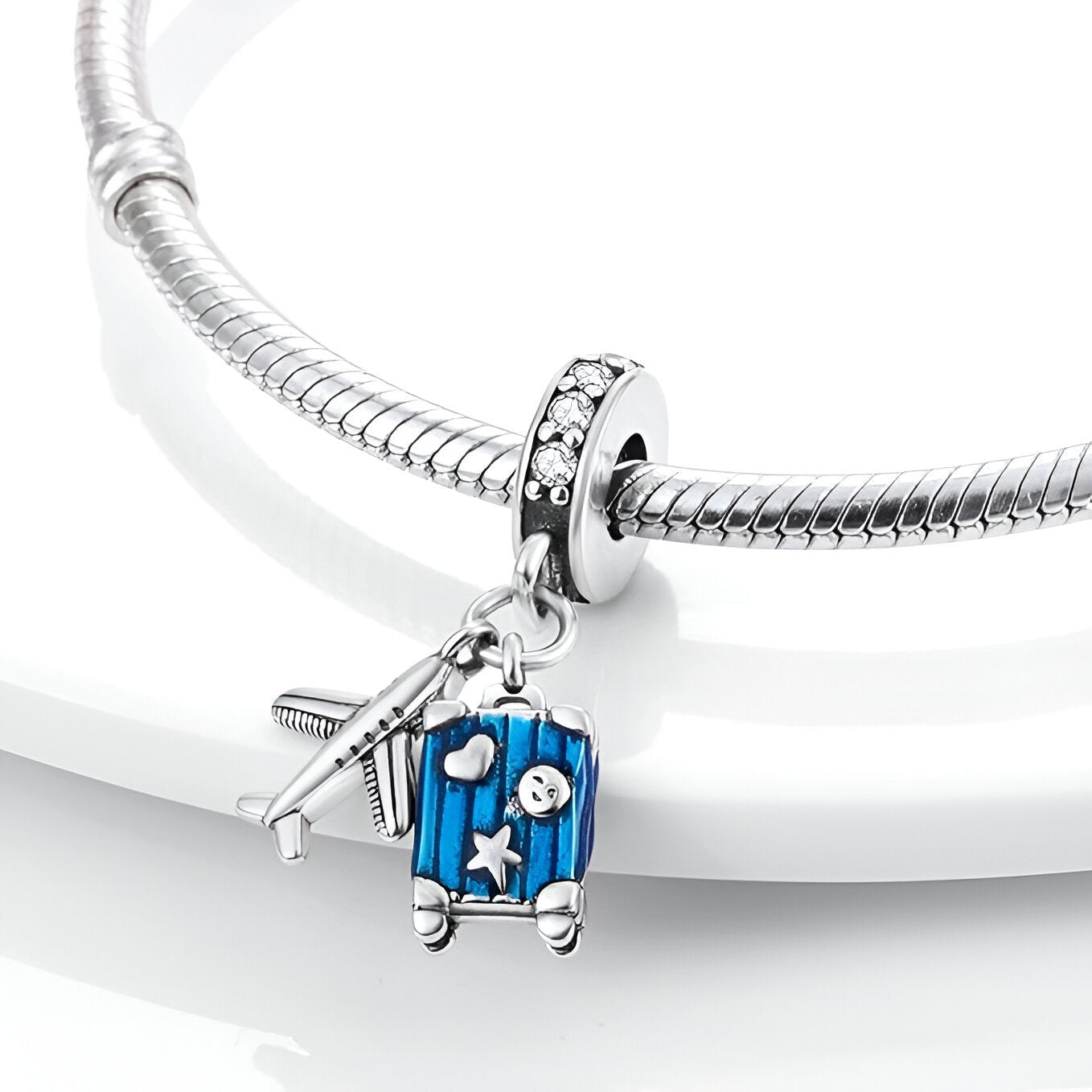 Charm pendentif argenté avion et valise bleue avec étoiles, sur bracelet serpent argenté.