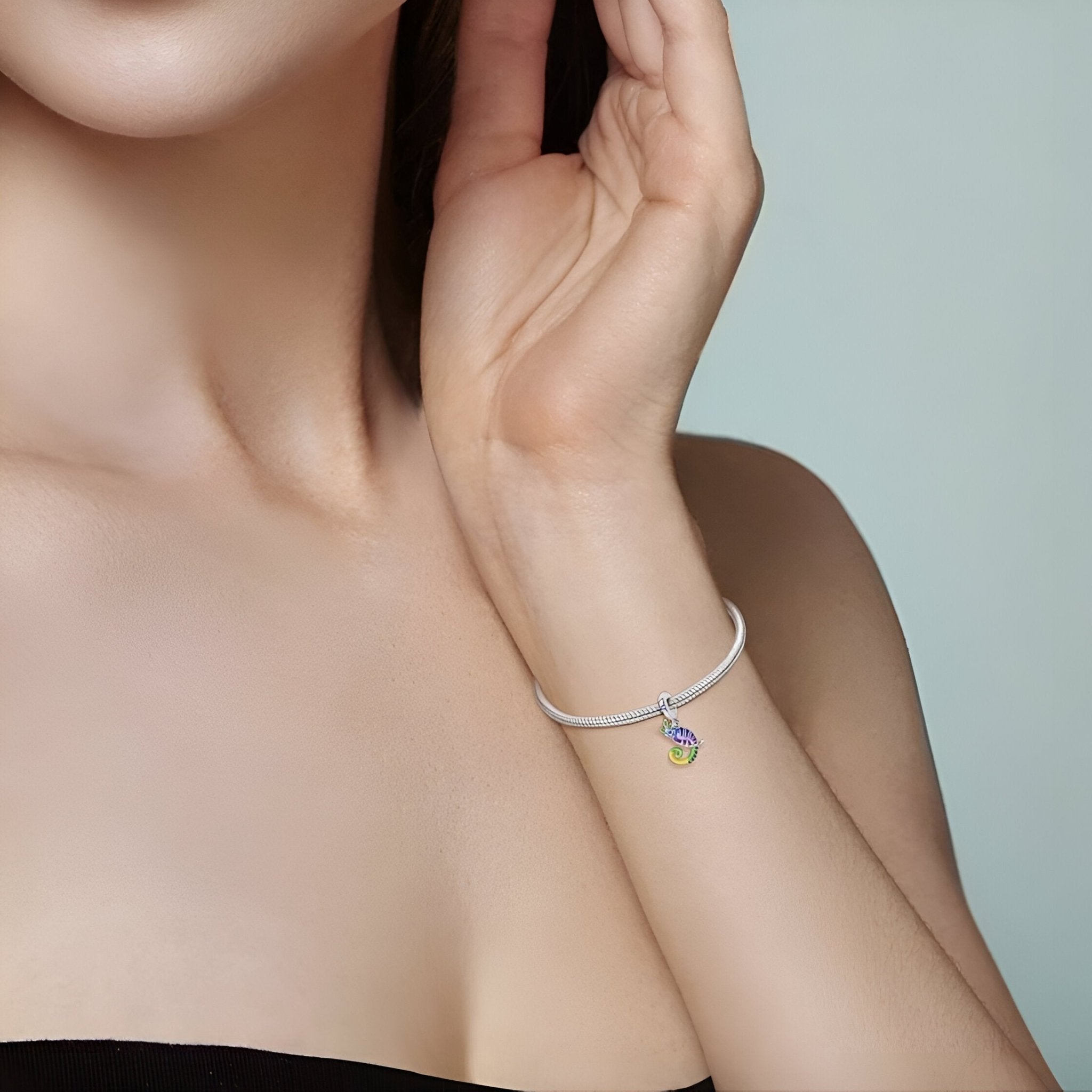 Bracelet blanc avec pendentif caméléon coloré, détails violets et jaunes, style délicat.