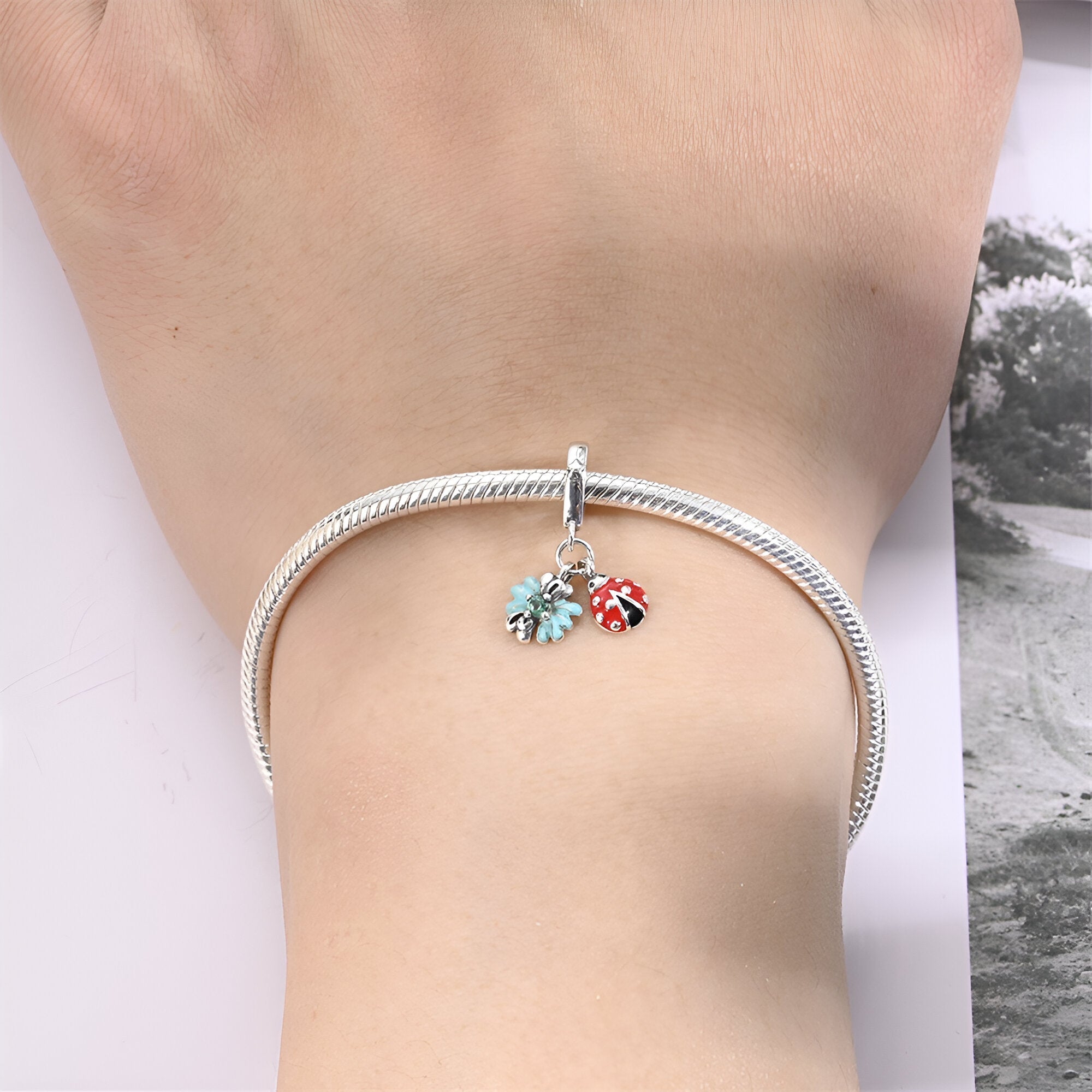 Bracelet argent avec pendentifs coccinelle rouge et feuille turquoise délicate.