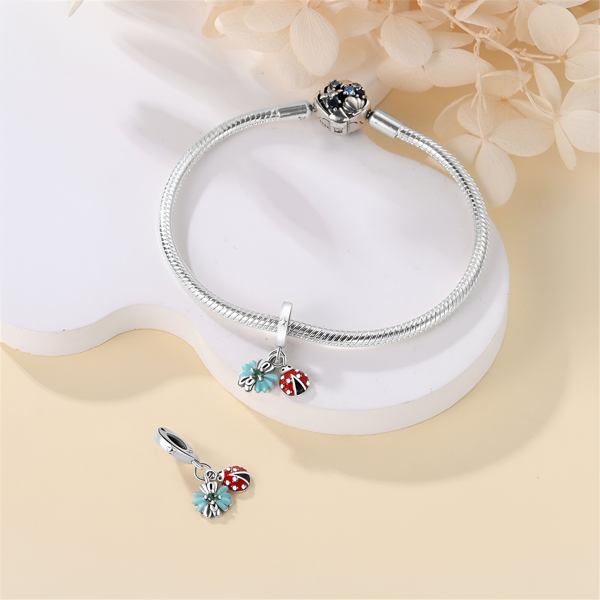 Bracelet argent avec pendentif coccinelle rouge et feuille verte détaillée.