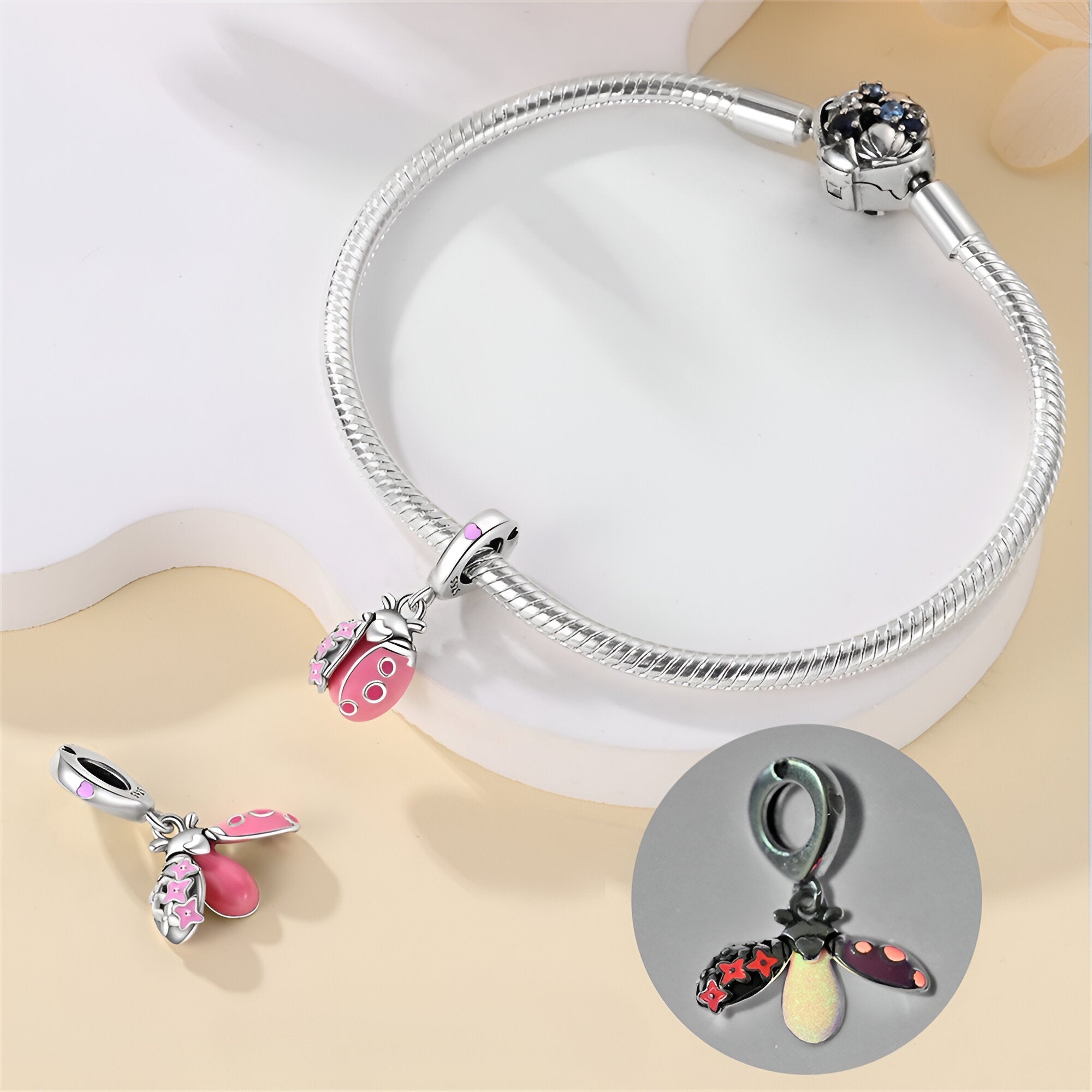 Bracelet argenté avec pendentif coccinelle rose et noir émaillée et détail lumineux.