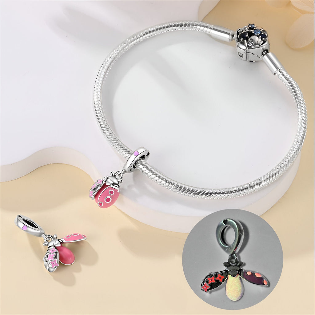 Bracelet argenté avec pendentif coccinelle rose et noir émaillée et détail lumineux.