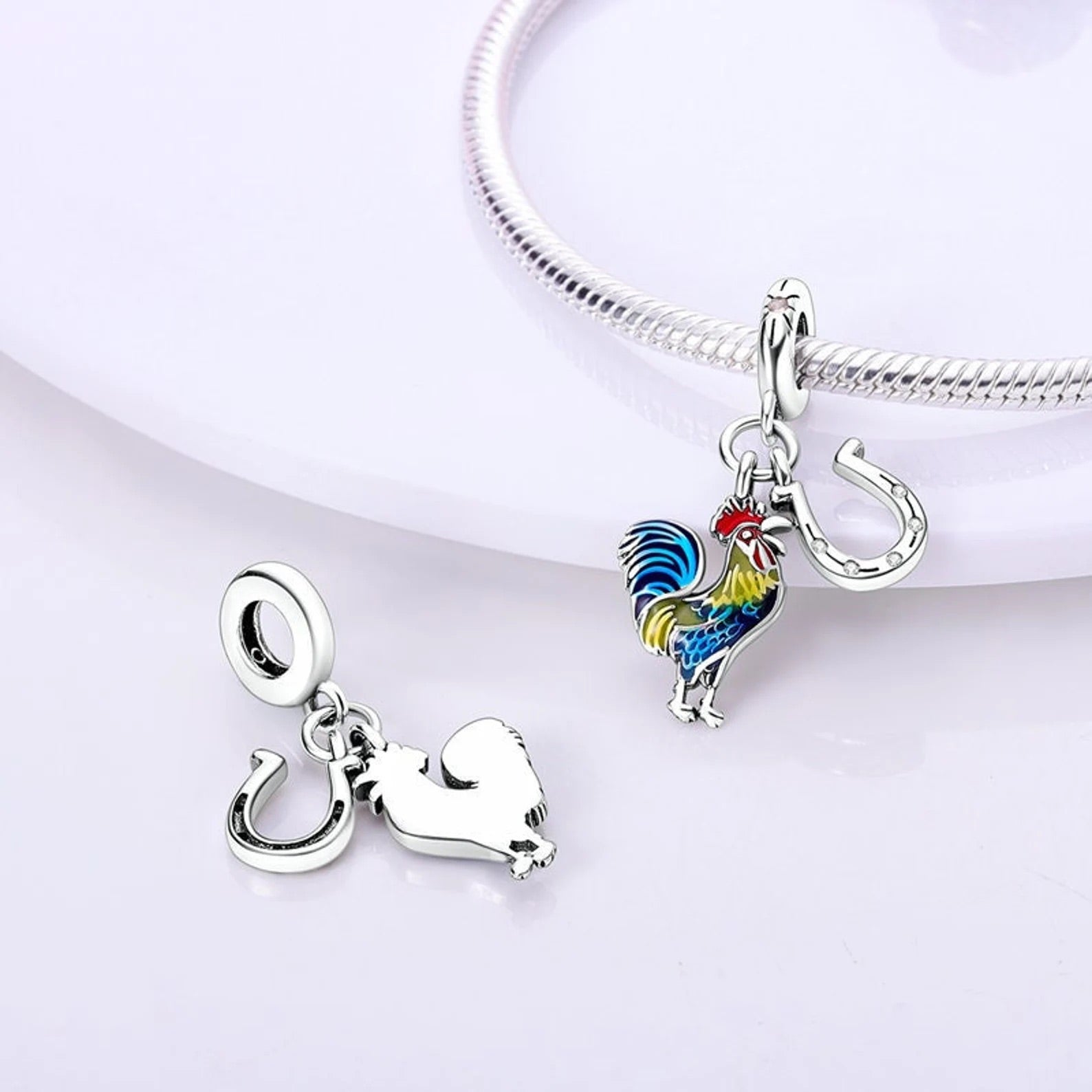 Pendentif coq coloré et fer à cheval en argent attachés à un bracelet serpent argenté.