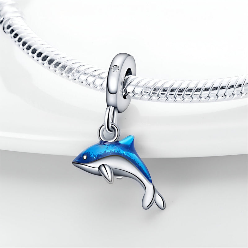 Charm pendentif dauphin bleu argenté suspendu à un bracelet serpent en argent brillant.