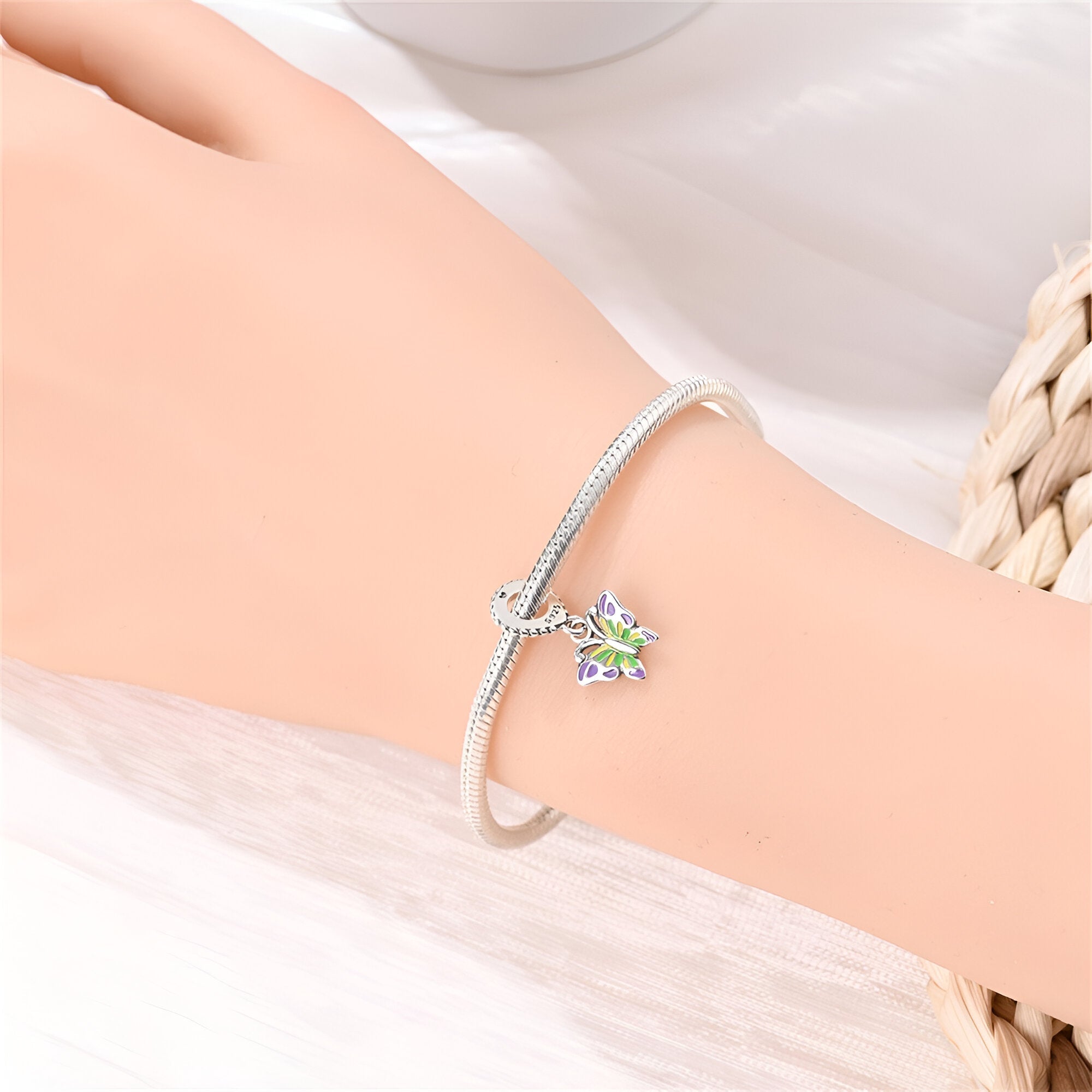 Bracelet argenté avec pendentif papillon translucide aux reflets irisés, style délicat et féminin.