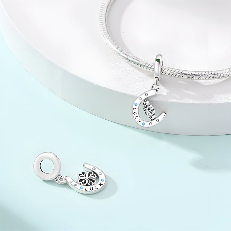 Pendentif fer à cheval argenté avec trèfle à quatre feuilles et strass blancs, style porte-bonheur.