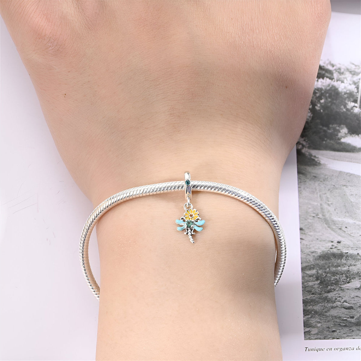 Bracelet argent avec pendentif libellule colorée sur marguerite blanche et jaune.