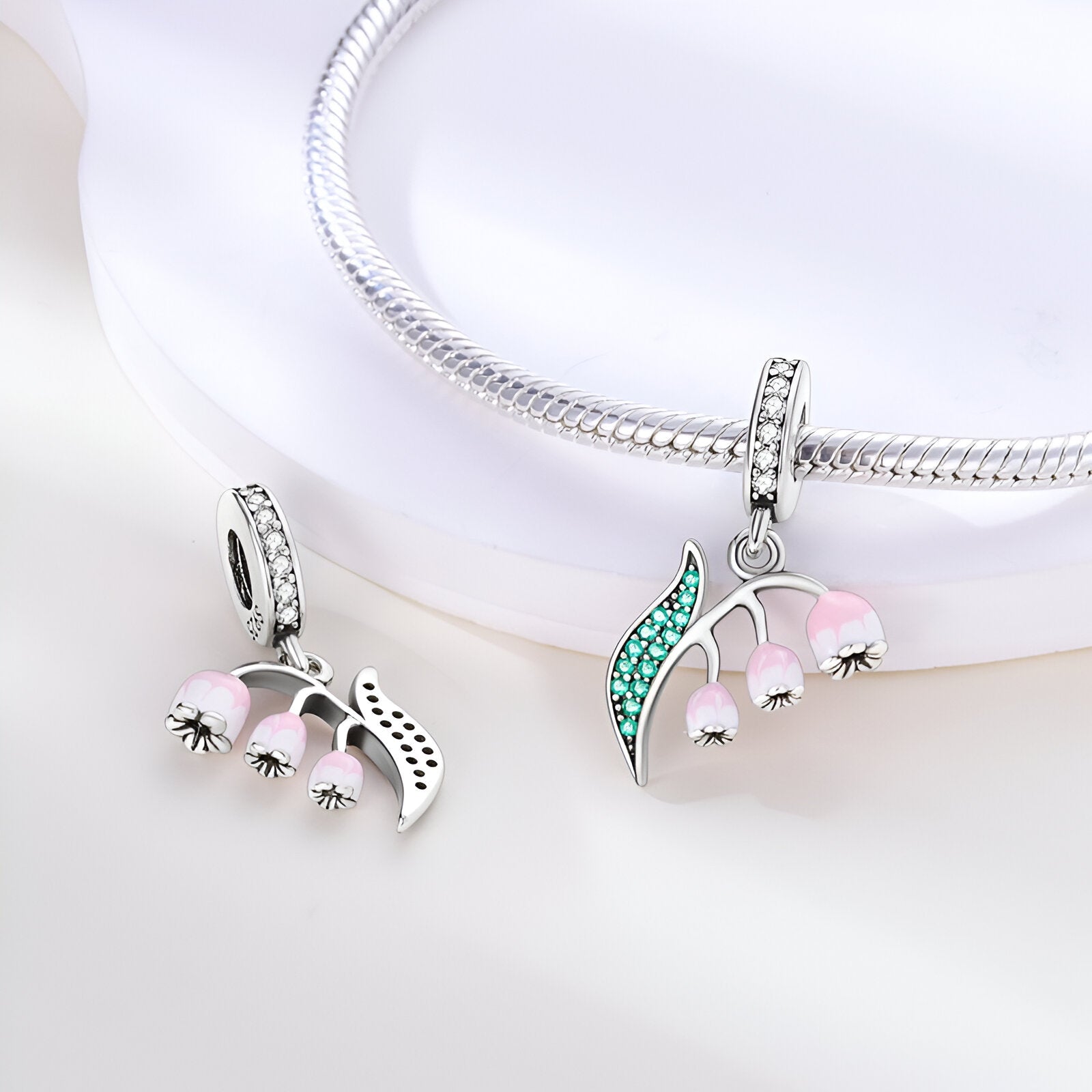 Charm pendentif muguet en argent avec clochettes roses et feuilles serties de pierres vertes.
