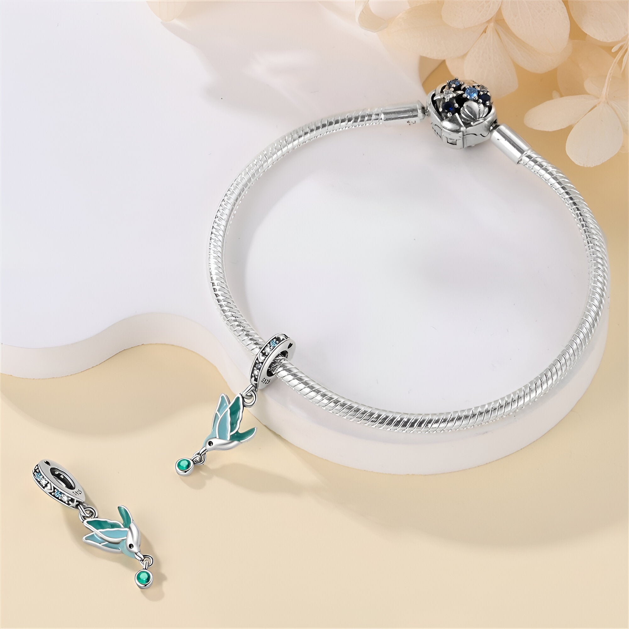 Bracelet argenté avec pendentif oiseau bleu et turquoise en émail, design délicat et moderne.