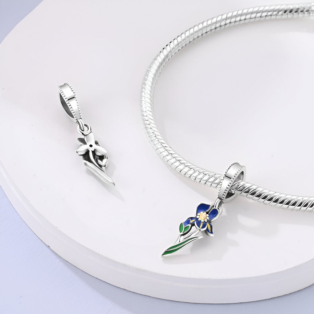 Pendentif charme orchidée coloré bleu et vert en métal argenté sur chaîne serpent argentée, détail fin et élégant.