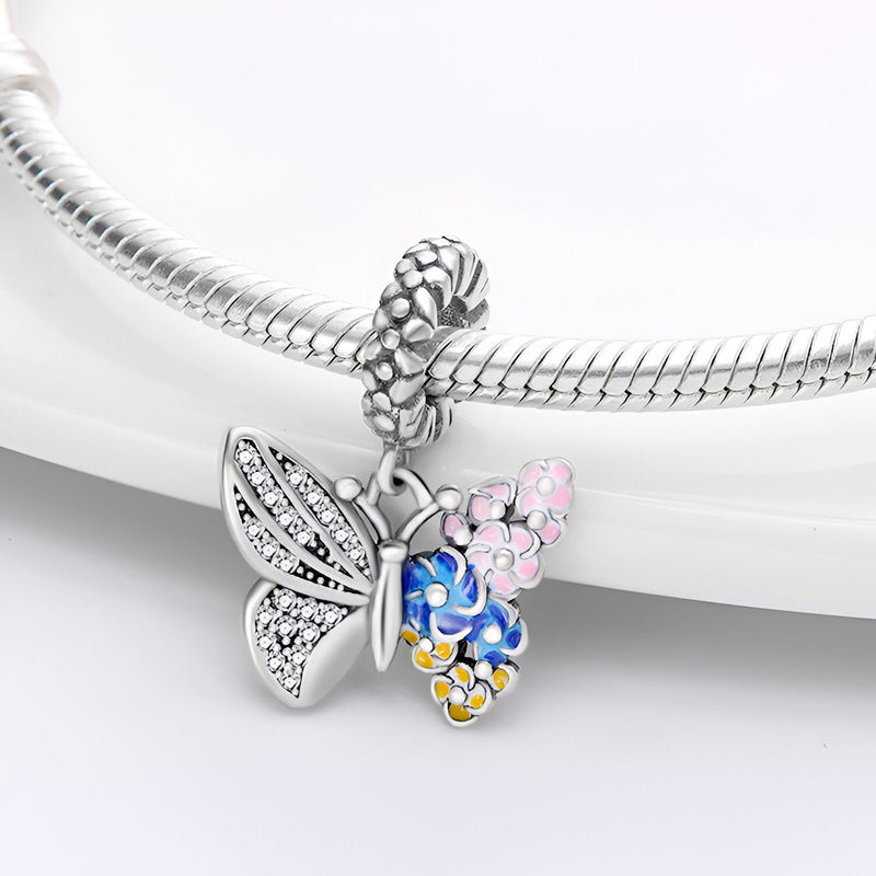 Pendentif papillon argent avec ailes fleurie rose, bleue et jaune sur bracelet serpent en argent.