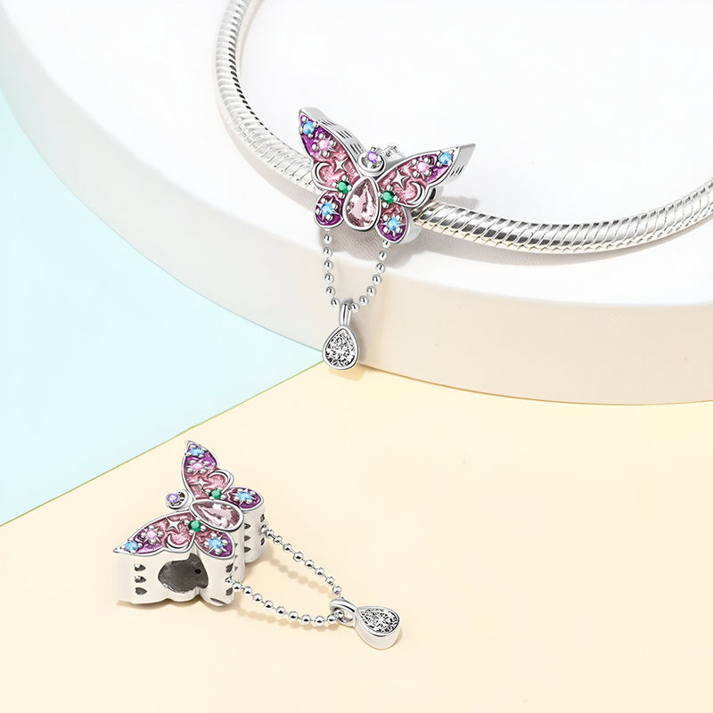 Pendentif papillon argenté orné de cristaux rose et bleu sur chaîne serpent brillante.