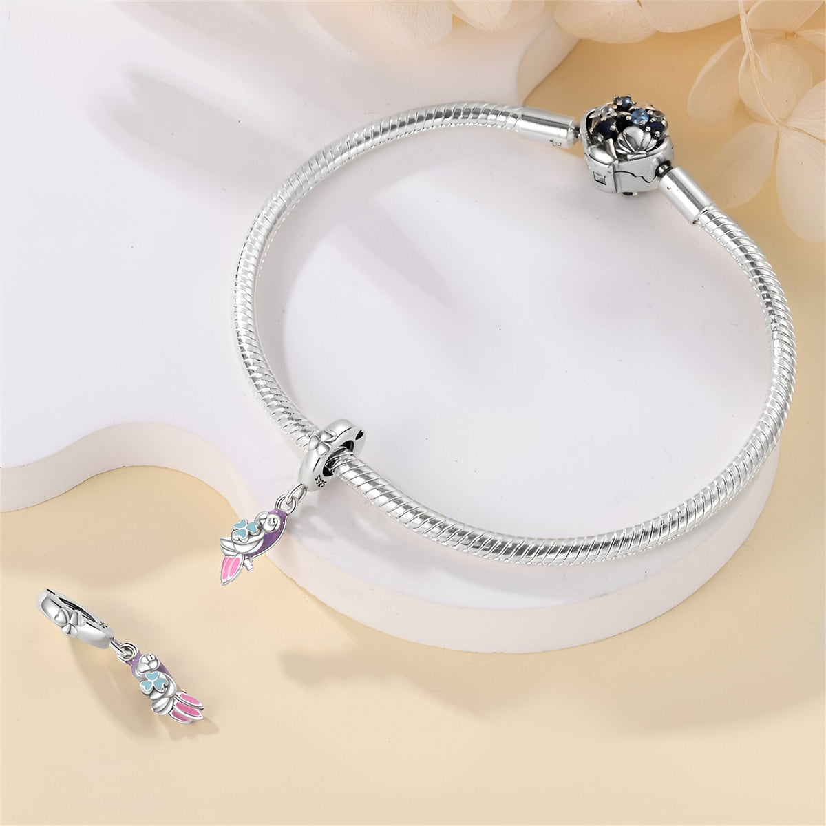 Bracelet argent avec pendentif perroquet coloré et détails roses et bleus.