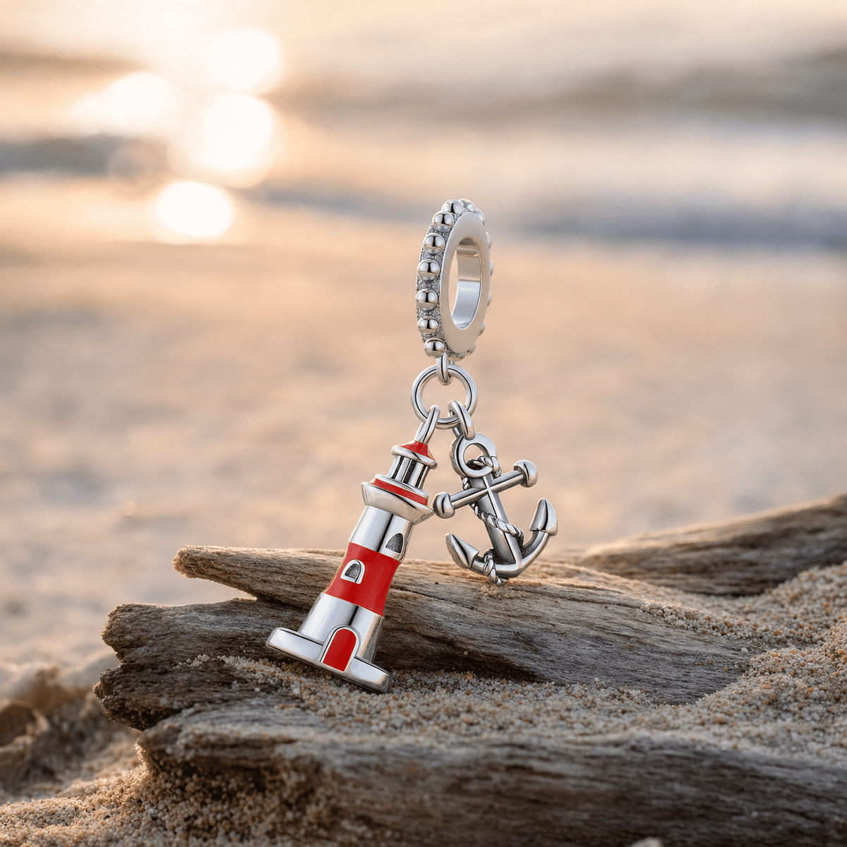 Charm pendant phare et ancre marine posé sur du bois flotté au bord de la mer au coucher du soleil