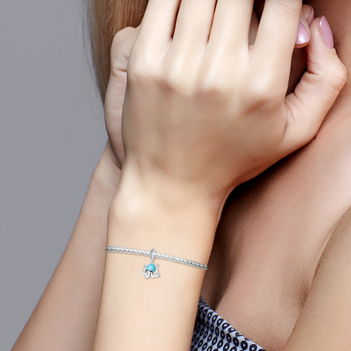Bracelet argent avec pendentif pieuvre bleue délicate porté au poignet féminin.