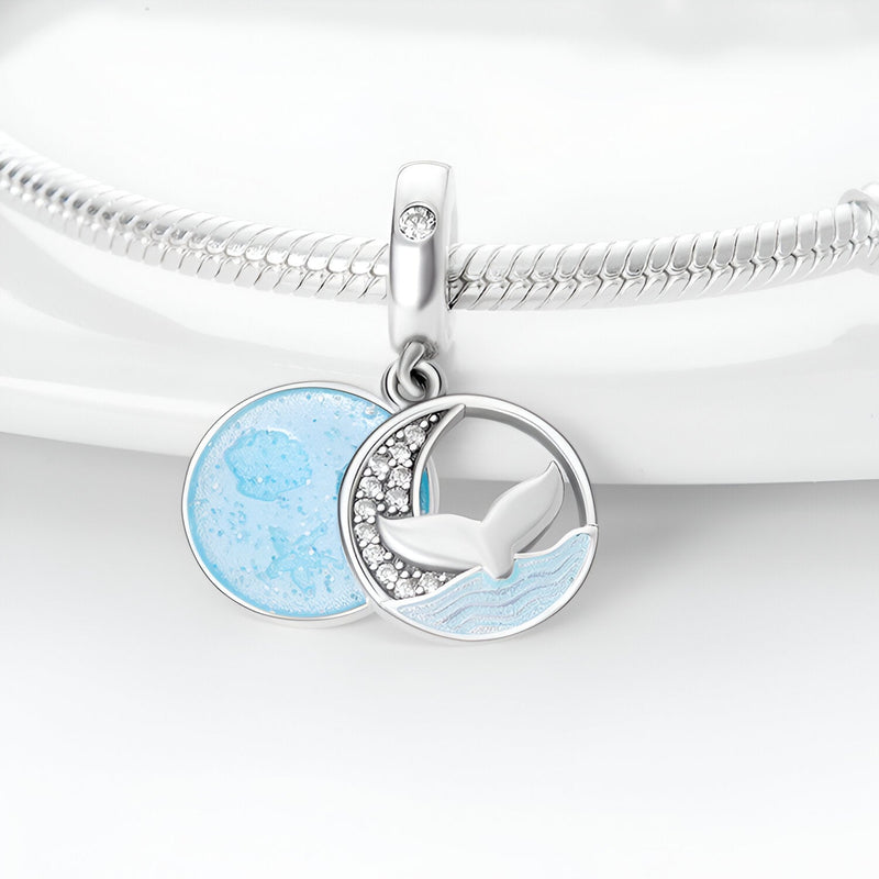 Charm pendentif argent avec queue de baleine et cercle bleu océan texturé sur bracelet serpent.