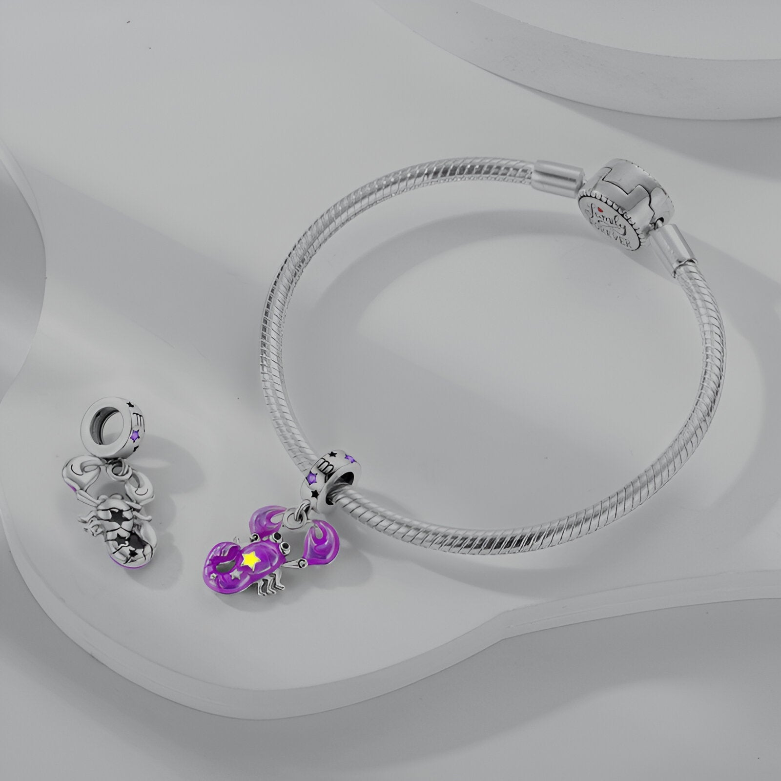 Bracelet argenté avec pendant charme signe Balance violet et deux breloques argentées supplémentaires.