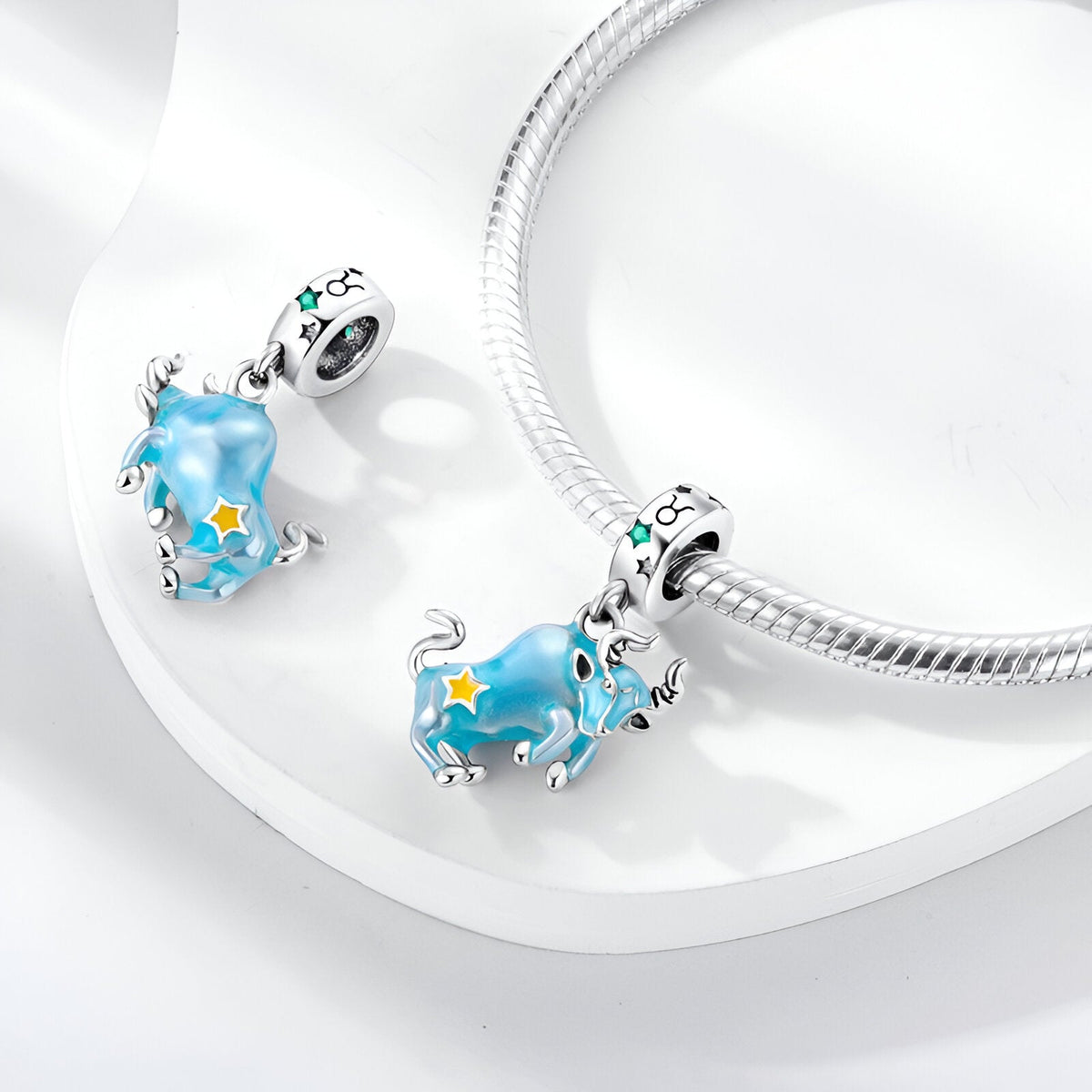 Pendentif charme Taureau bleu avec étoiles jaunes et argent, modèle Nevena, sur bracelet serpent argenté.