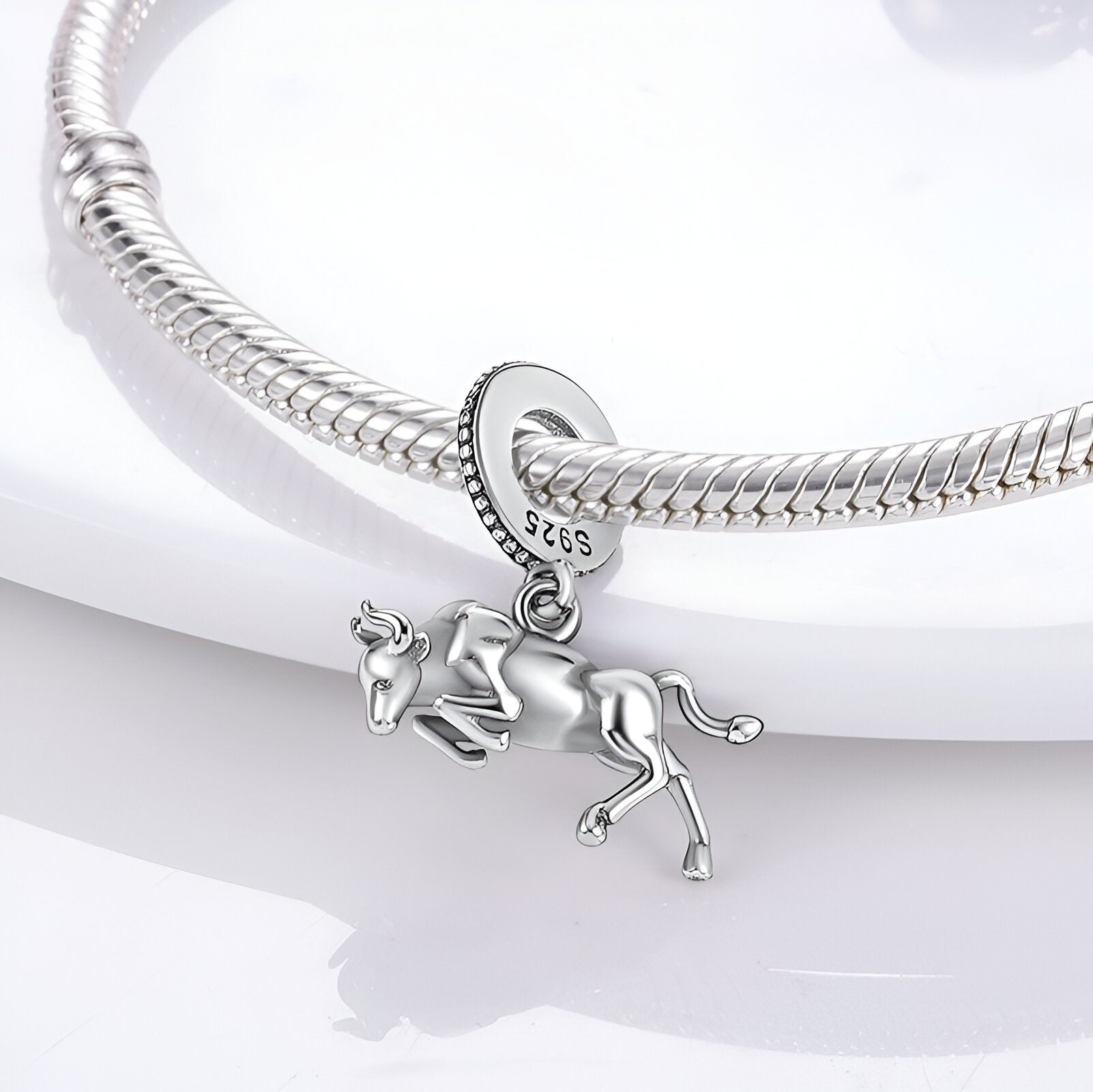 Charm pendentif taureau sprintant en argent poli suspendu à un bracelet serpent argenté.