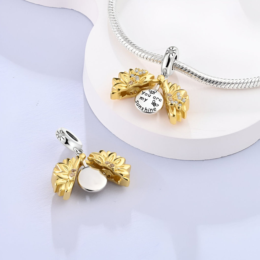 Charm pendentif tournesol ouvert en métal doré avec breloque ronde argentée gravée.