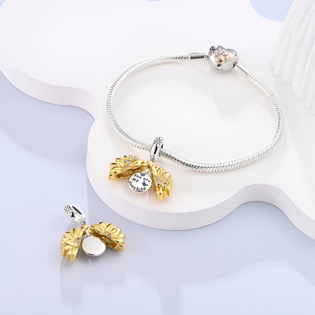 Charm pendentif tournesol doré et argenté avec strass, porté sur bracelet argenté serpent.