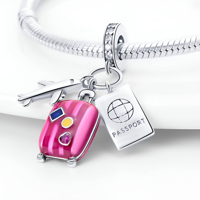 Charm pendentif en argent avec valise rose, passeport gravé et avion, style voyage.