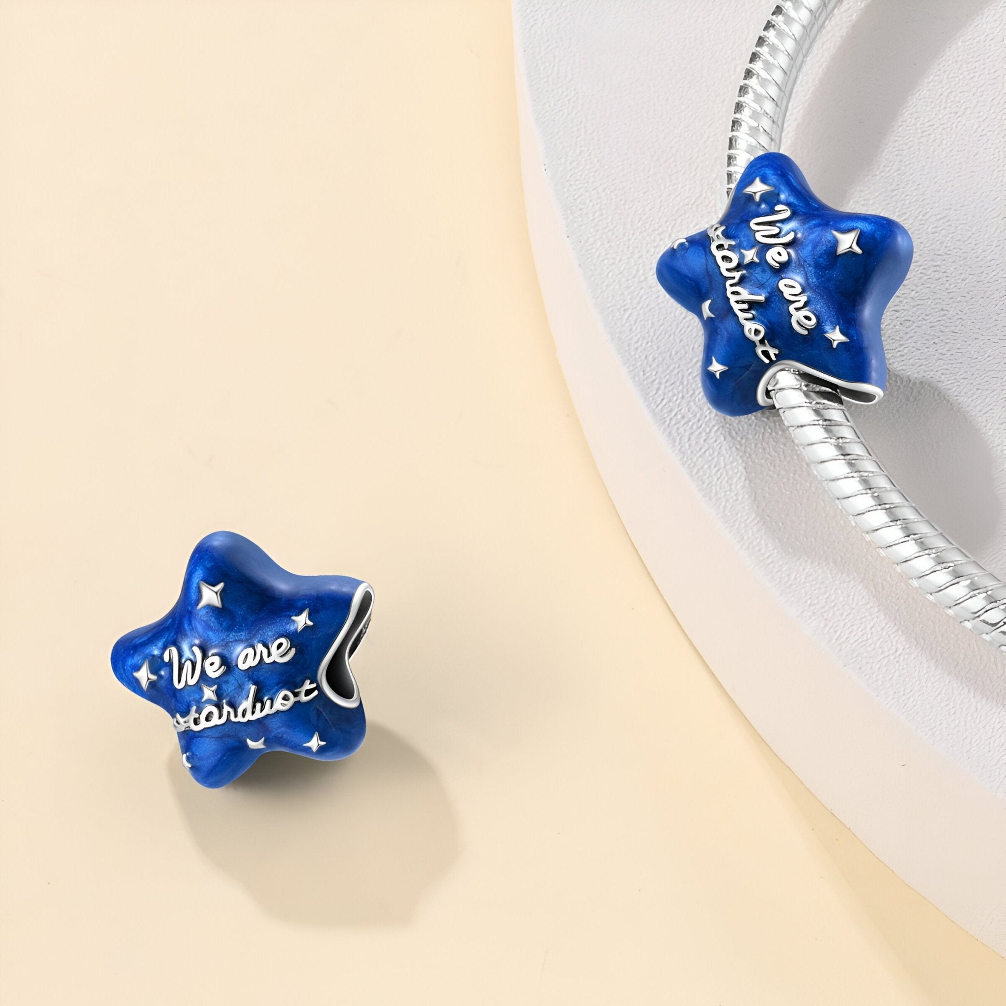 Charm étoile bleu nuit en émail avec inscription dorée "We are stardust" sur bracelet argenté.