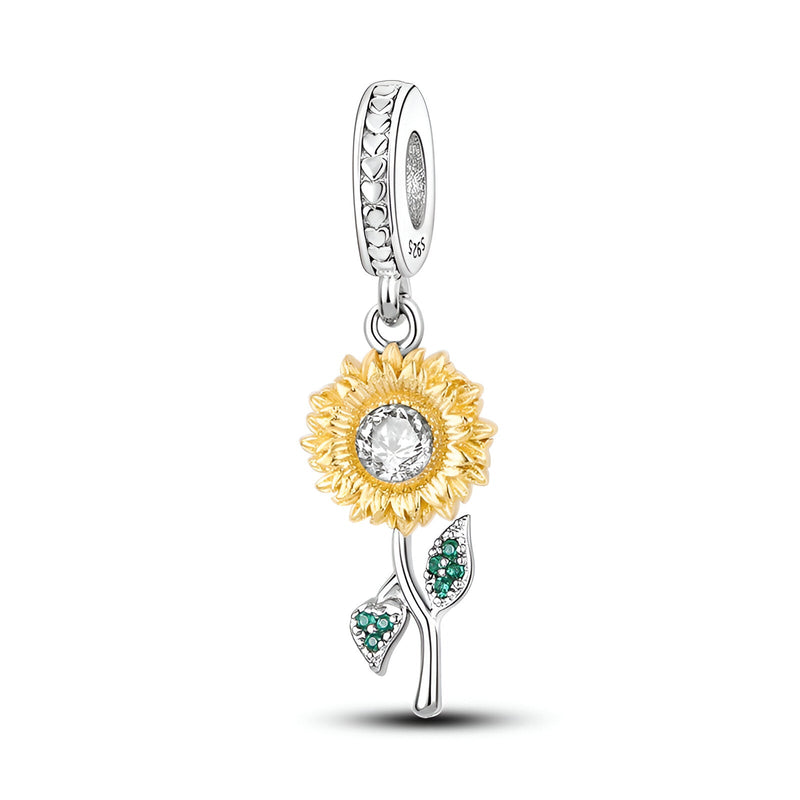 Charm pendentif tournesol doré avec pierre centrale claire et tige argentée ornée de feuilles vertes.