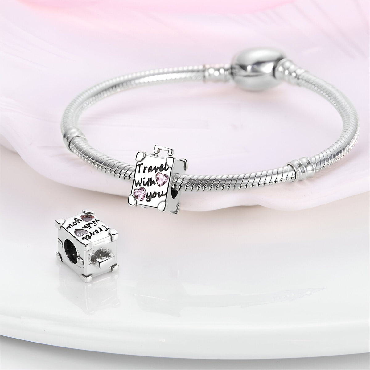 Charm valise argentée avec gravure "Travel with you" et bracelet serpent en argent brillant.