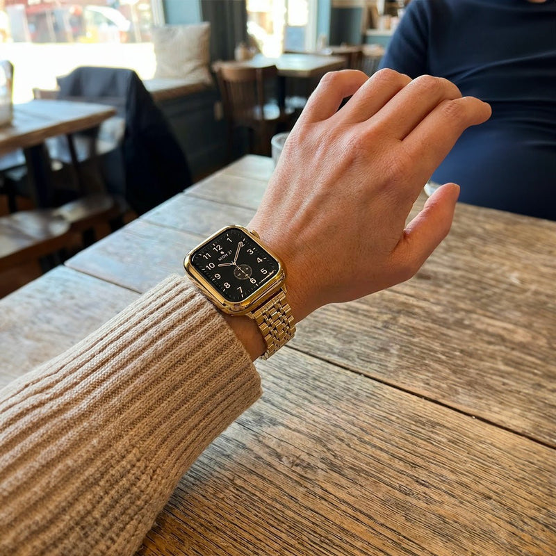 Coque intégrale en acier inoxydable doré brillant pour Apple Watch avec bracelet à maillons et fermeture déployante raffinée.
