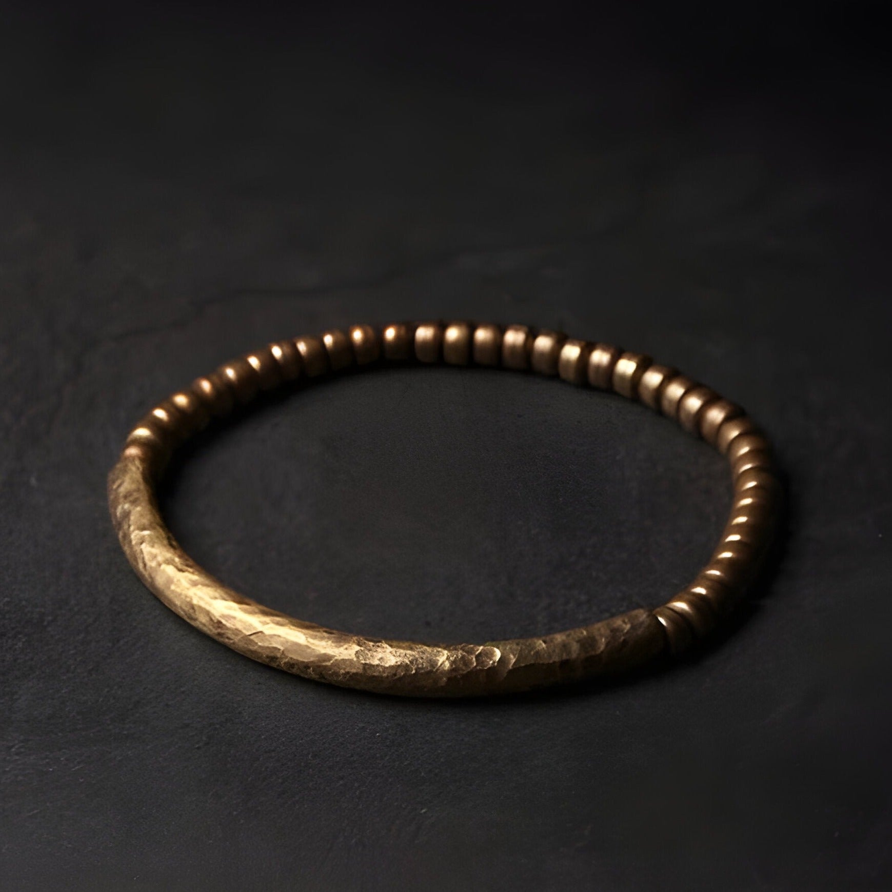 Bracelet mixte en cuivre martelé et perles bois marron sur fond noir.