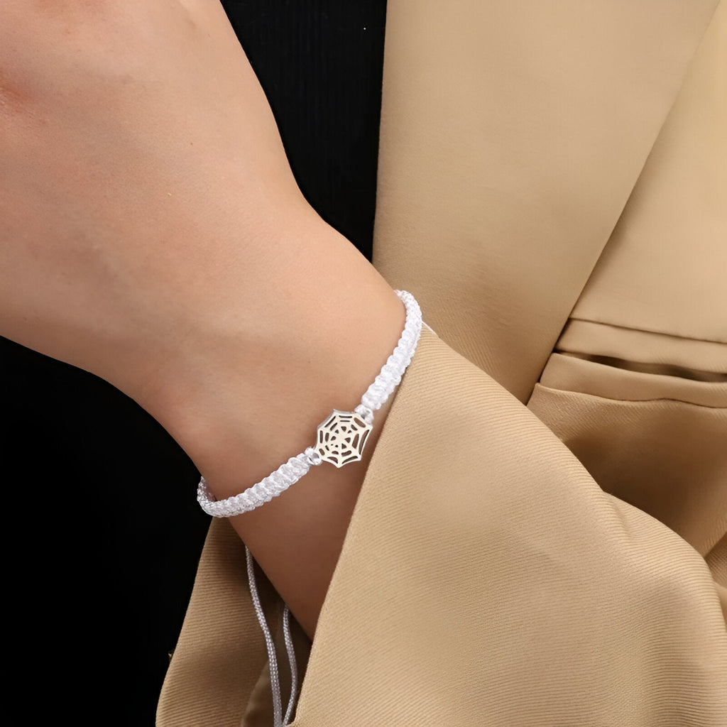 Bracelet cordon blanc avec pendentif araignée en métal argenté, style tressé fin.