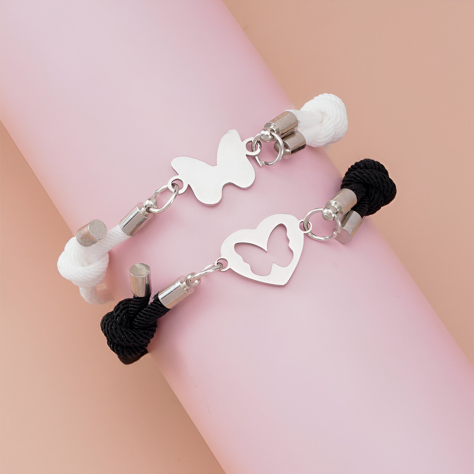 Duo de bracelets cordon noir et blanc avec pendentifs métal cœur et papillon élégant.